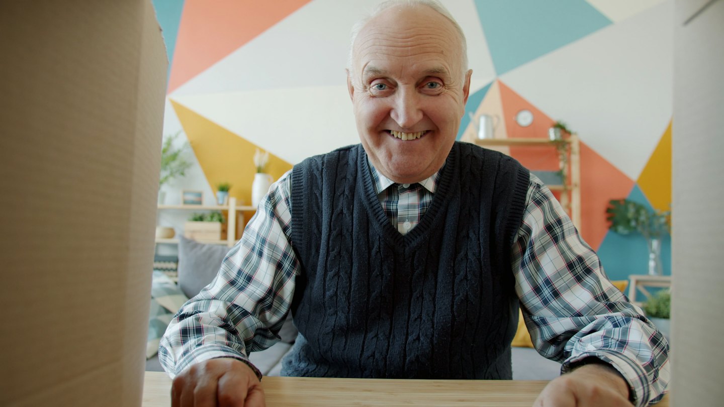 Man joyfully opening a cardboard package on a wooden table.